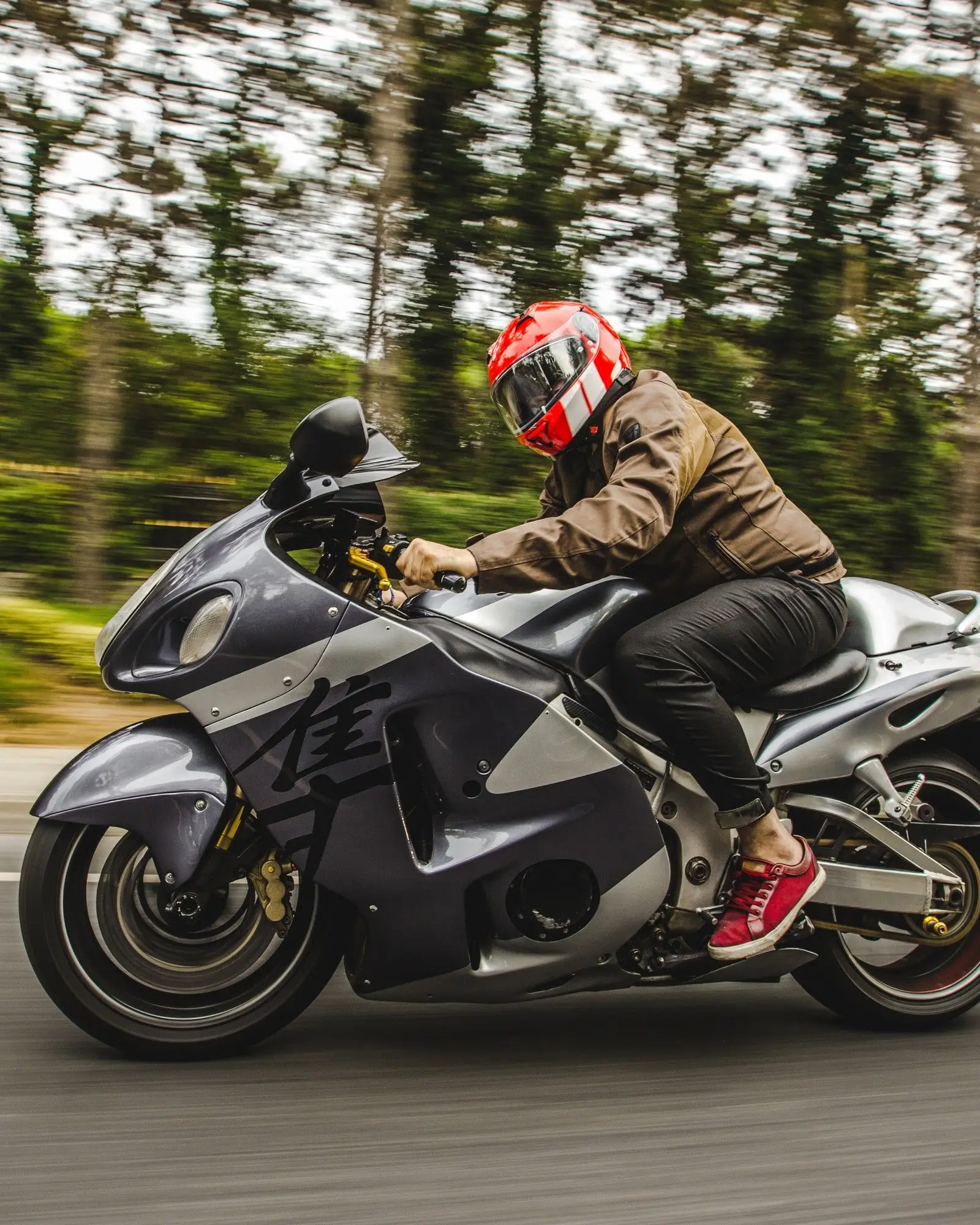 Moto esportiva carenada em alta velocidade numa estrada cercada de árvores